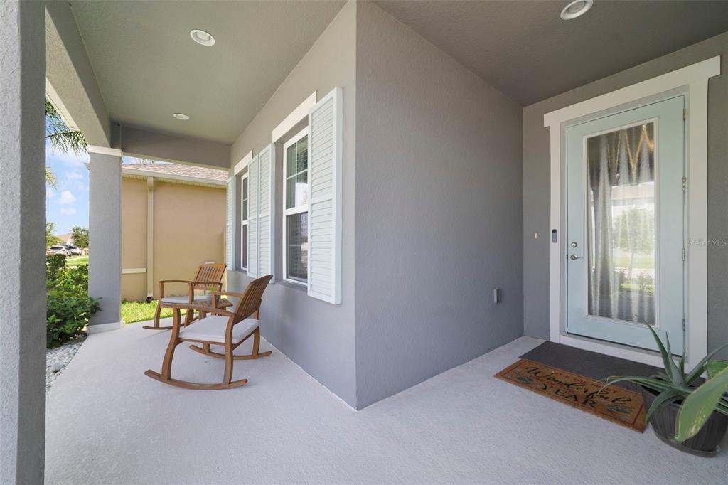 A covered front porch features two wooden rocking chairs, a light blue door, and shutters — 173 LAVENNA AVENUE, ST CLOUD, FL