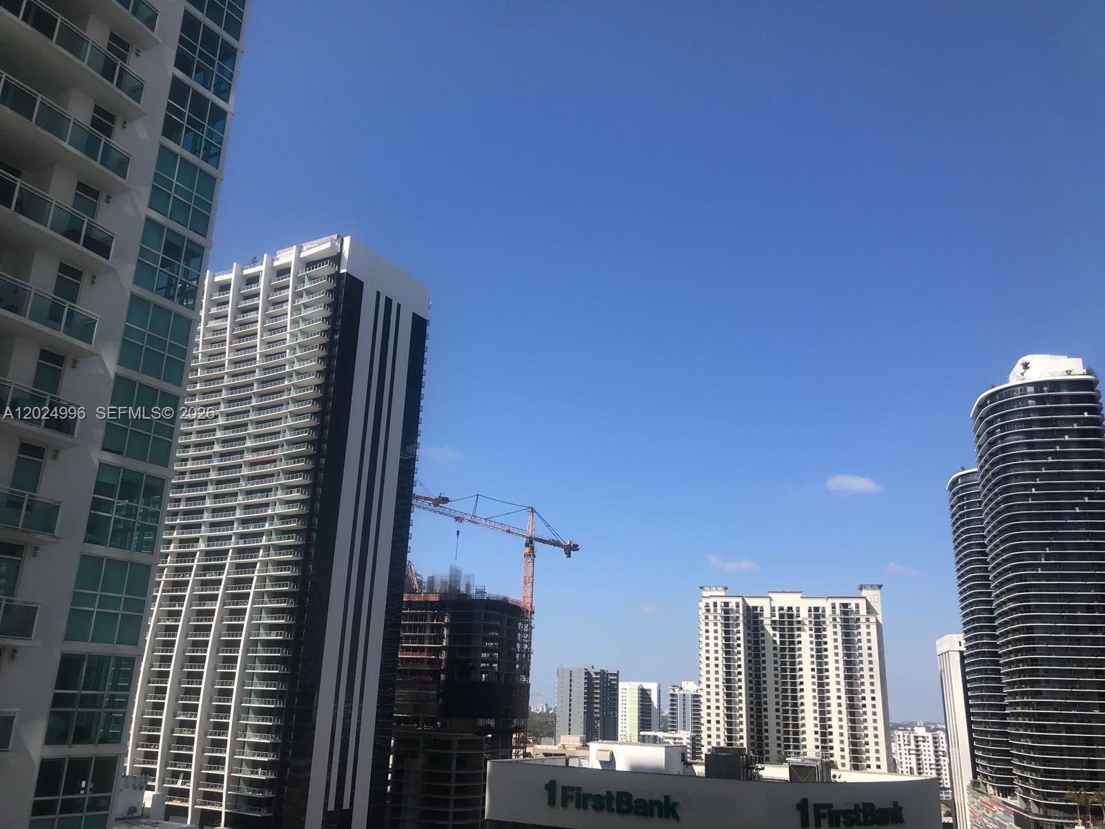 A view of several high-rise buildings and a construction crane under a clear blue sky — 950 Brickell Bay Dr # 2000, Miami FL 33131, MIAMI, FL