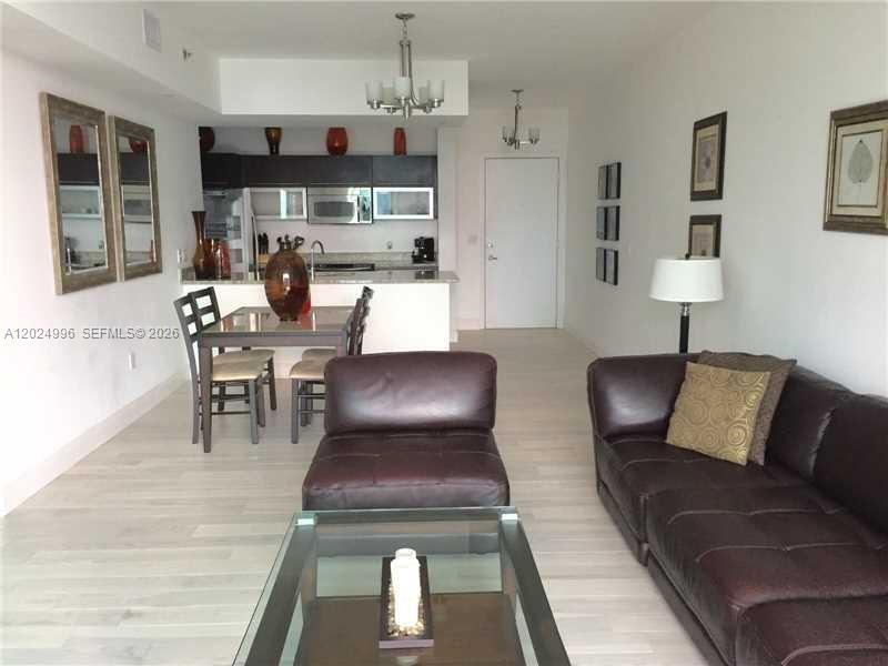 An open-concept living and dining area features dark leather furniture and a modern kitchen — 950 Brickell Bay Dr # 2000, Miami FL 33131, MIAMI, FL