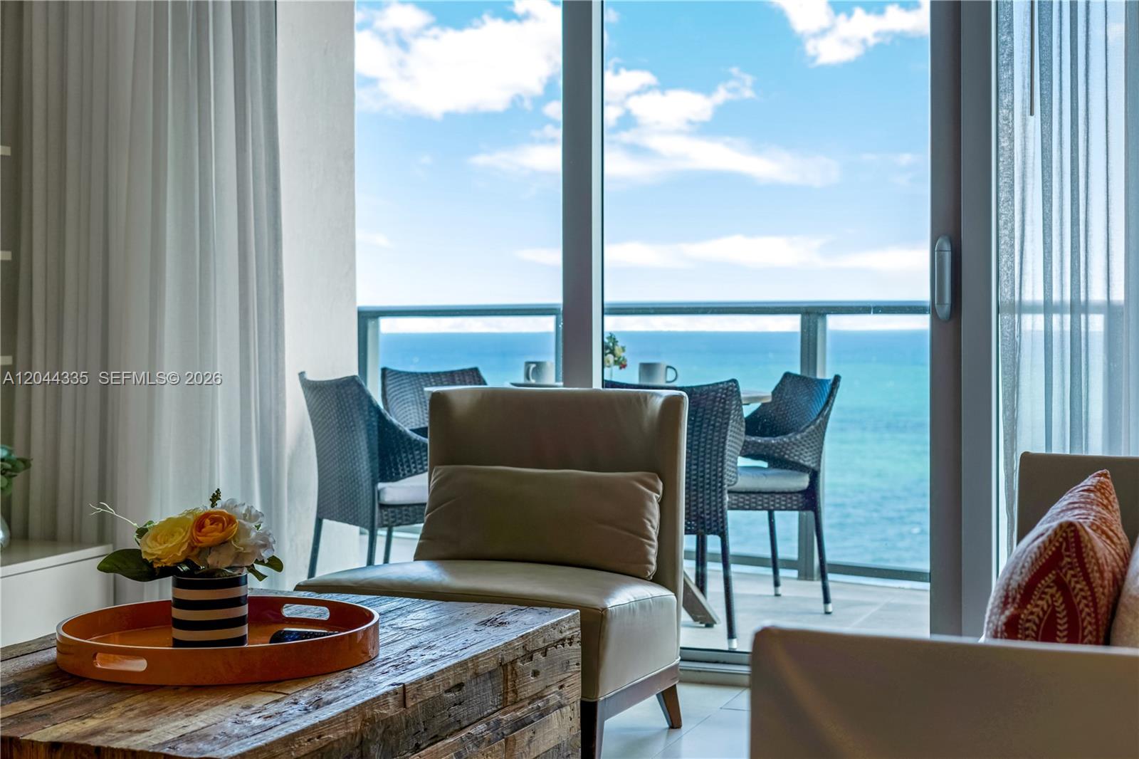 A living room features a wooden coffee table and a balcony overlooking the ocean — 4111 S Ocean Dr # 1405, Hollywood FL 33019, HOLLYWOOD, FL