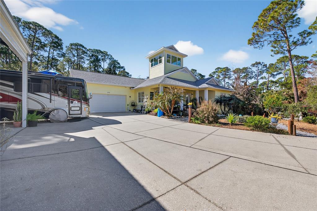A yellow house with a cupola and an attached garage sits behind a large driveway — 615 ART CENTER AVENUE, NEW SMYRNA BEACH, FL