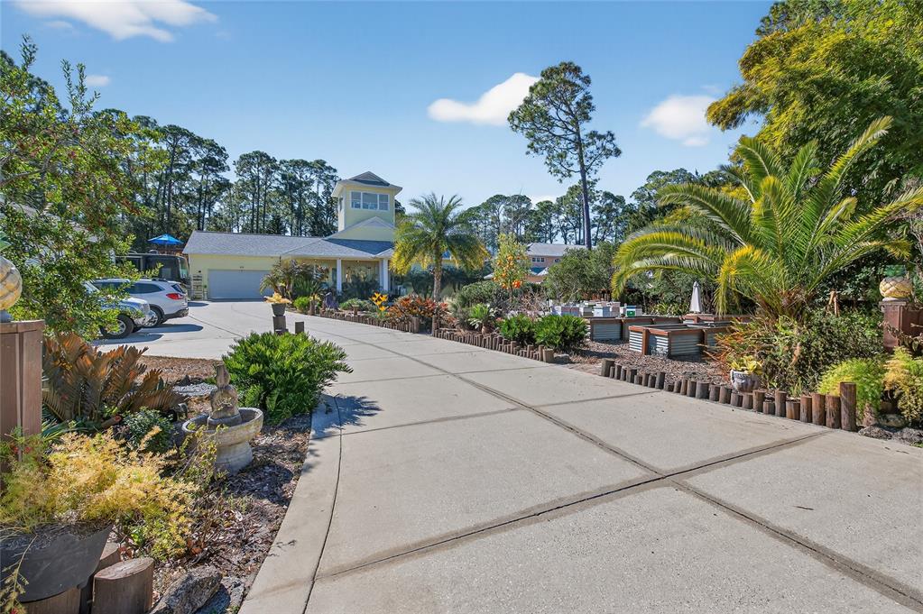 A long concrete driveway leads to a yellow house with a tower and palm trees — 615 ART CENTER AVENUE, NEW SMYRNA BEACH, FL