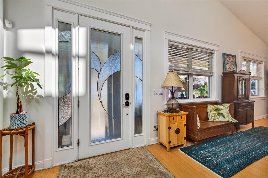 An entryway features a white front door with decorative glass, wood flooring, and wooden furniture — 615 ART CENTER AVENUE, NEW SMYRNA BEACH, FL
