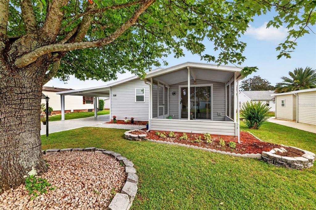 A single-story house with light gray siding, a screened-in porch, and a covered carport — 728 PRADO DRIVE, LADY LAKE, FL