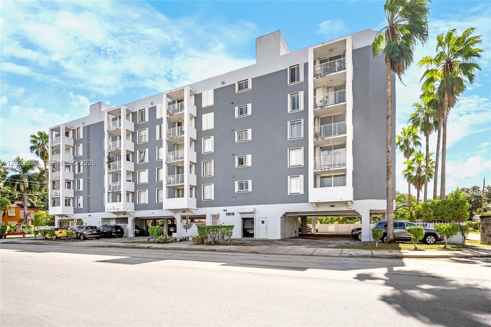 A multi-story gray and white apartment building with covered ground-level parking and palm trees — 1010 NW 11th St # 507, Miami FL 33136, MIAMI, FL