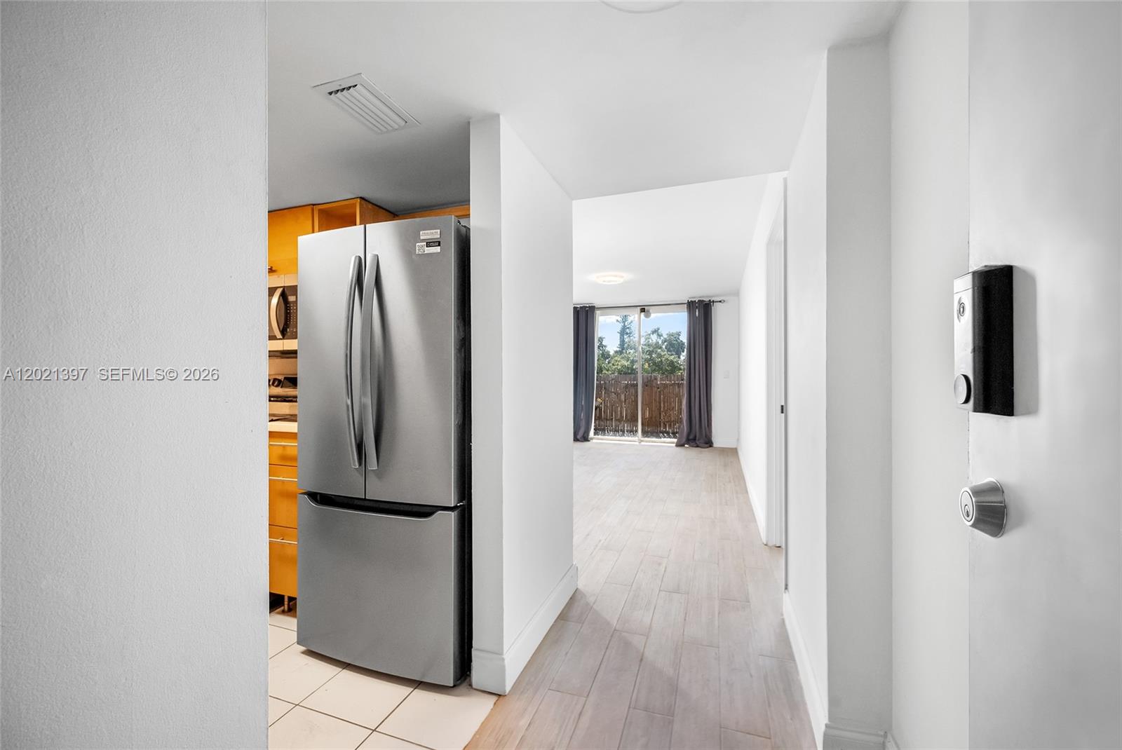 A stainless steel refrigerator sits in a kitchen area adjacent to a living space — 1010 NW 11th St # 507, Miami FL 33136, MIAMI, FL