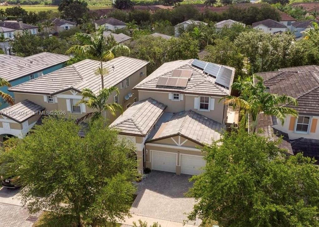 An aerial view shows a two-story suburban house with solar panels on the roof — 385 NE 36th Ave Rd, Homestead FL 33033, HOMESTEAD, FL