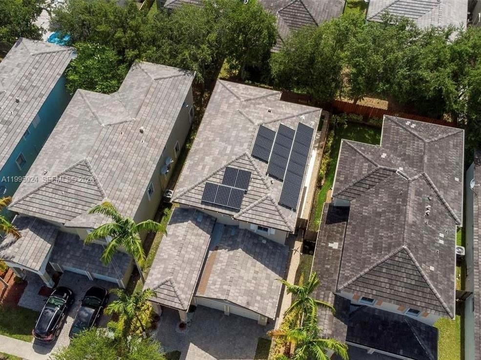 An aerial view shows three suburban houses with tiled roofs, one featuring solar panels — 385 NE 36th Ave Rd, Homestead FL 33033, HOMESTEAD, FL
