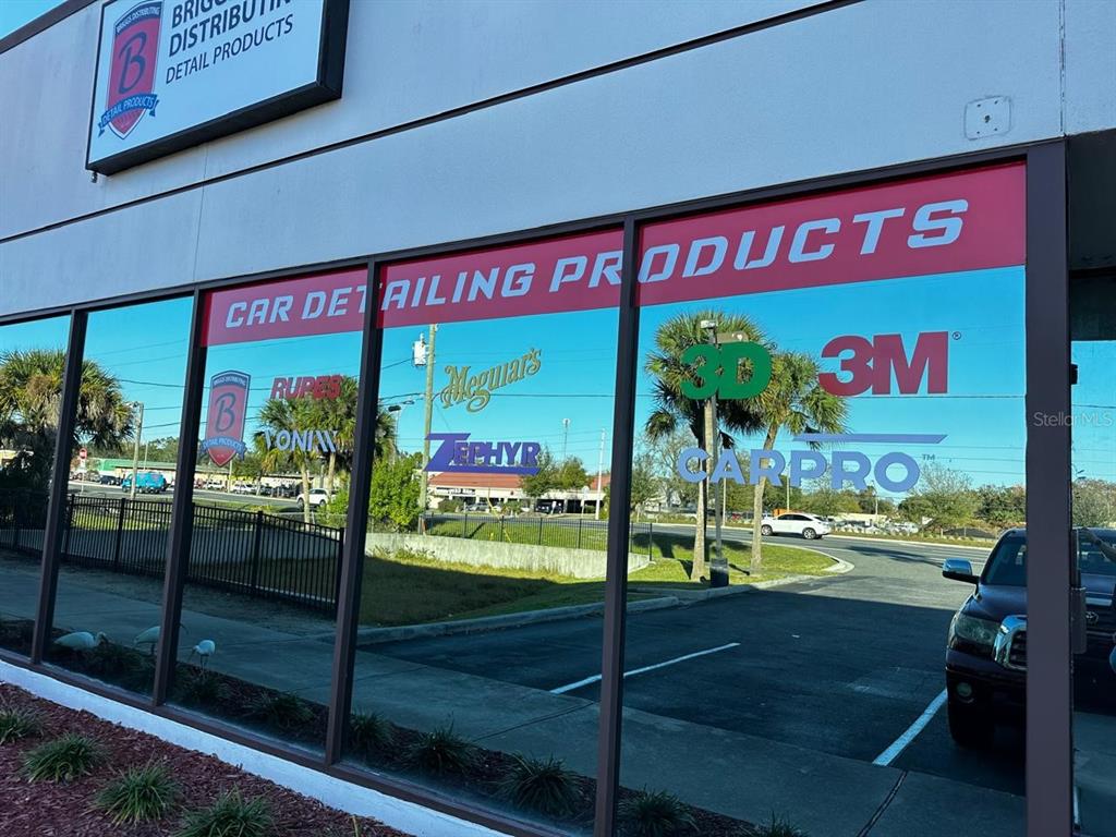 The exterior of a commercial building features large windows displaying various car detailing product brands — 3701 N JOHN YOUNG PARKWAY, ORLANDO, FL