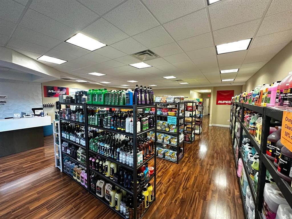 A retail store interior features shelves stocked with car detailing products on wood-look flooring — 3701 N JOHN YOUNG PARKWAY, ORLANDO, FL