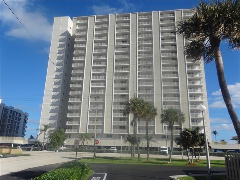 A tall, multi-story residential apartment building with balconies stands under a blue sky — 750 N Ocean Boulevard # 1704, Pompano Beach FL 33062, POMPANO BEACH, FL