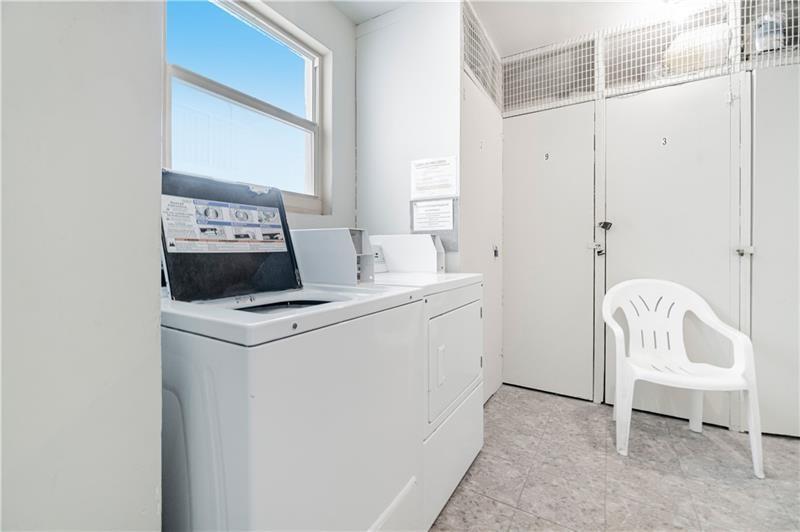 A laundry room features a white washer and dryer, a plastic chair, and storage lockers — 750 N Ocean Boulevard # 1704, Pompano Beach FL 33062, POMPANO BEACH, FL