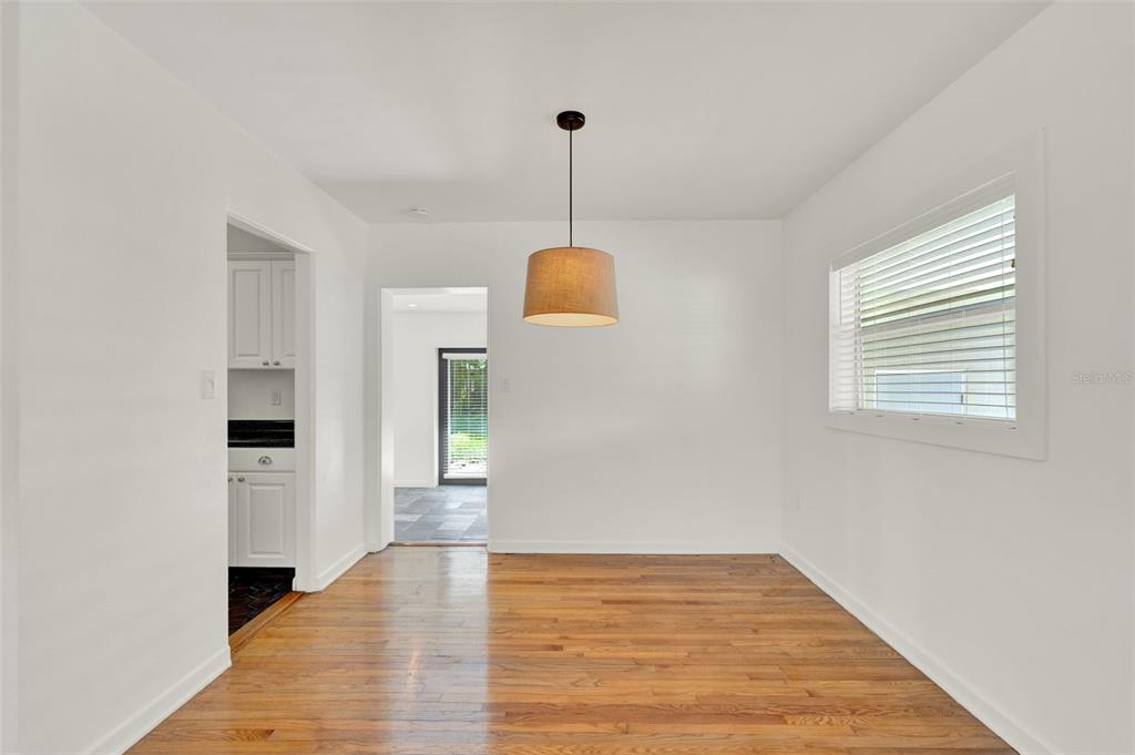 A dining room with hardwood floors, a pendant light, and a view into the kitchen — 3345 LILA DRIVE, ORLANDO, FL