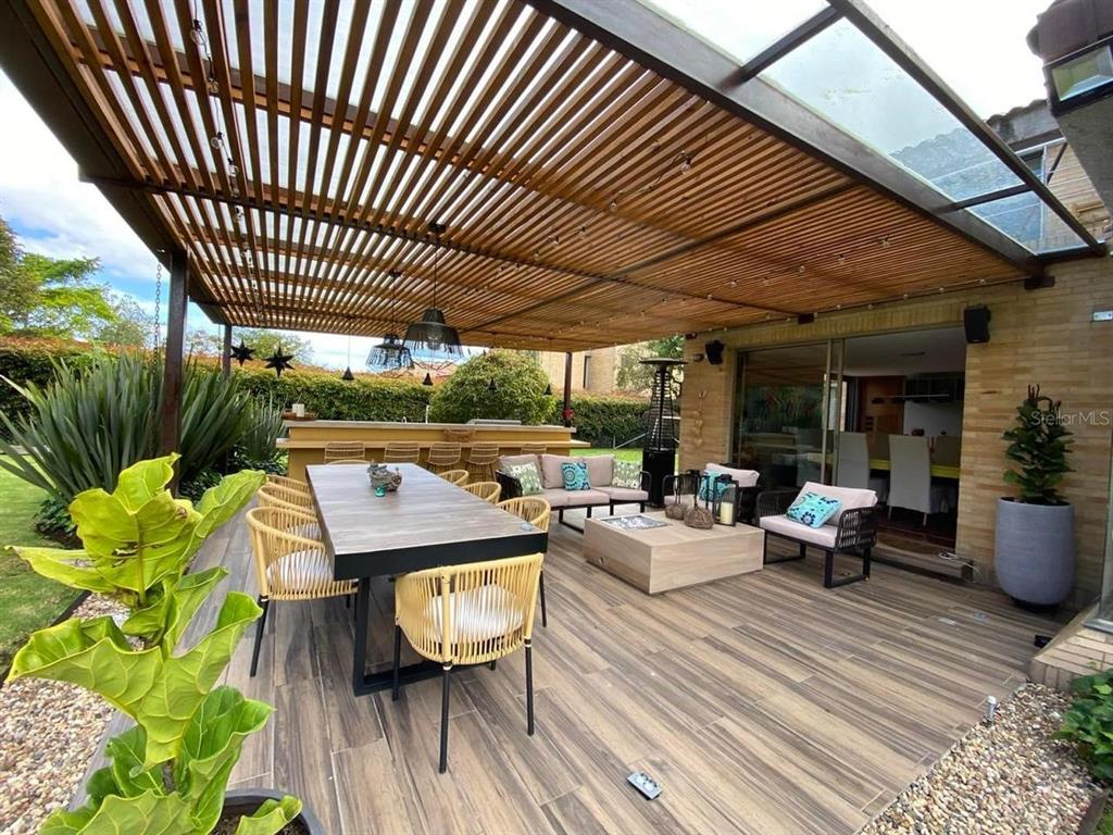 A covered outdoor patio features a dining set, lounge furniture, and a built-in bar area — 47 CARRERA 47, BOGOTA, NY