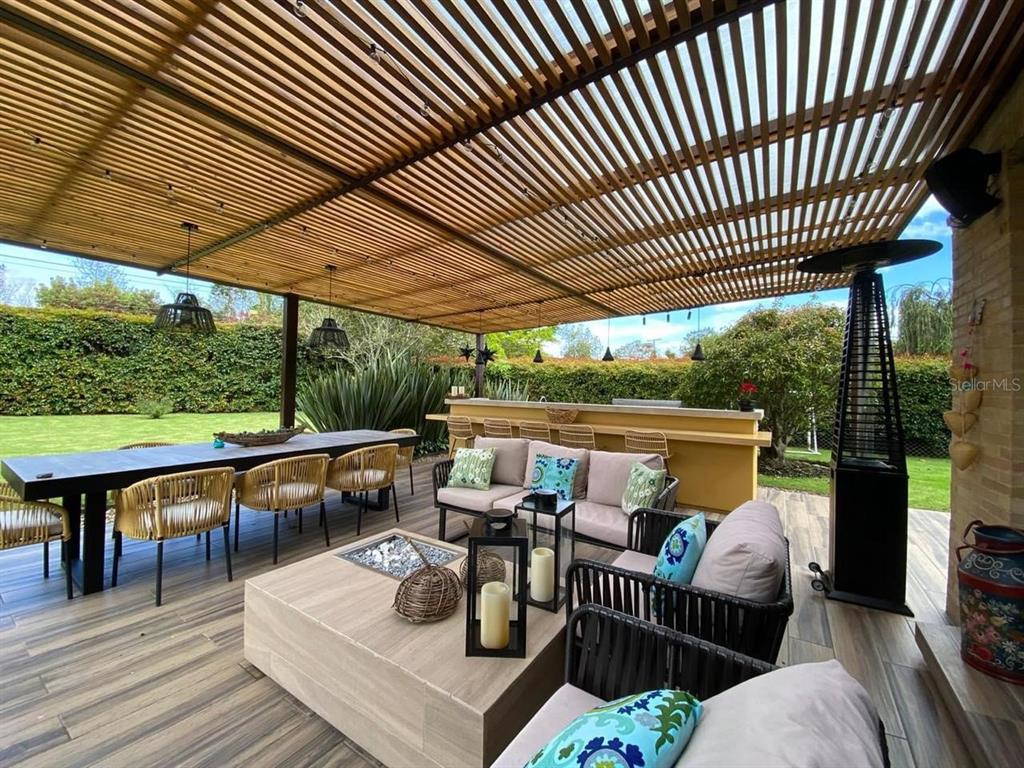 A covered outdoor patio features a dining table, lounge seating, a fire pit, and bar — 47 CARRERA 47, BOGOTA, NY