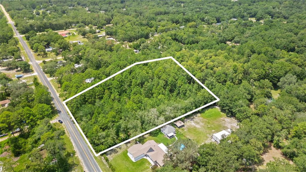 An aerial view shows a rectangular, wooded lot outlined in white next to a road — 150 SESAME STREET, MIDDLEBURG, FL