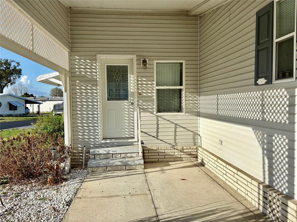 A concrete porch leads to a white front door with a decorative glass insert — 6133 GRAND OAKS DRIVE SE, WINTER HAVEN, FL
