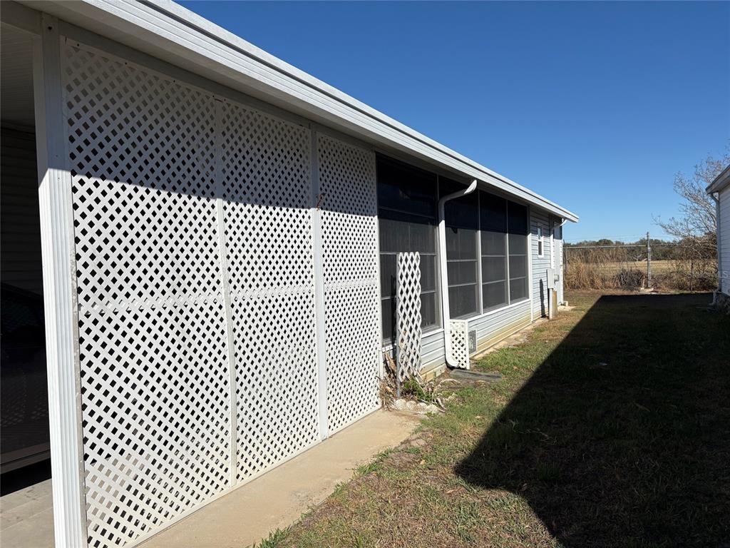 A white lattice screen encloses a side patio area next to a screened-in porch — 6133 GRAND OAKS DRIVE SE, WINTER HAVEN, FL