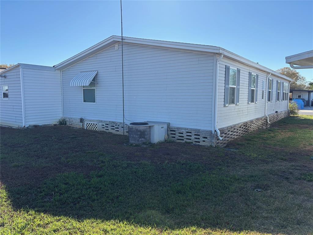 The exterior of a light-colored mobile home with vinyl siding and a stone-patterned skirting — 6133 GRAND OAKS DRIVE SE, WINTER HAVEN, FL