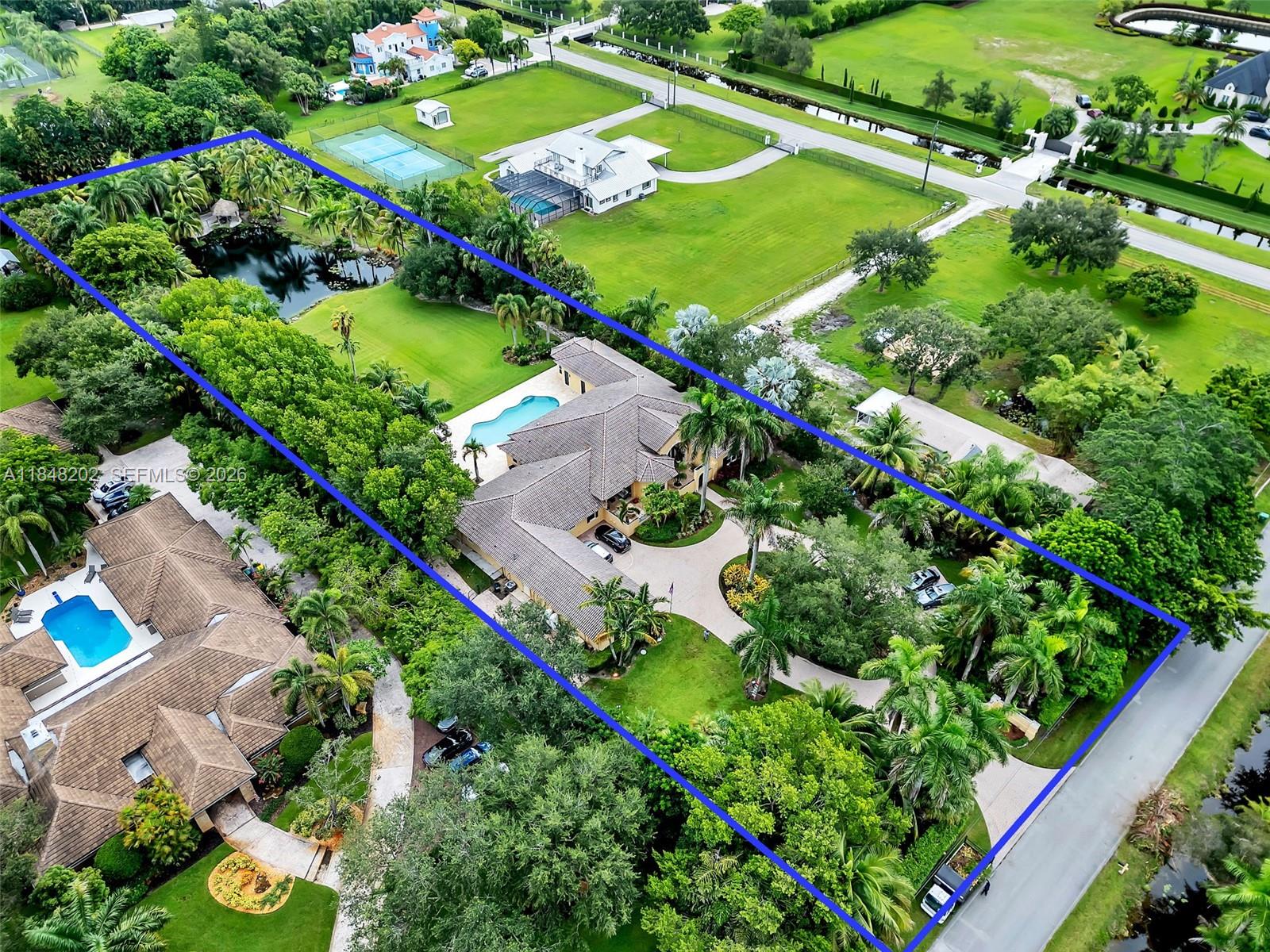 An aerial view shows a large house with a pool and pond on a landscaped lot — 14211 Sunset Ln, Southwest Ranches FL 33330, SOUTHWEST RANCHES, FL