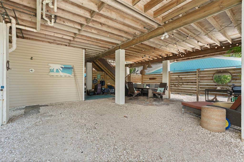 A covered outdoor patio area with a gravel floor, seating, and exposed wooden ceiling beams — 2517 AVENUE C, BRADENTON BEACH, FL