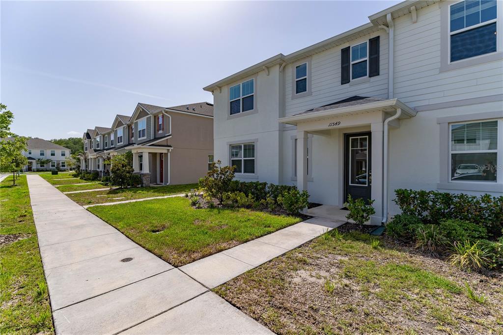 A row of two-story townhouses with light-colored siding and concrete walkways in a suburban neighborhood — 11549 STRAITS WAY, ORLANDO, FL