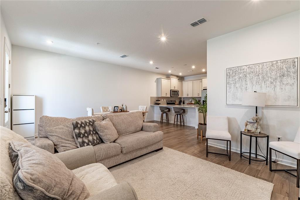 A living room with a beige sofa opens into a kitchen with a breakfast bar — 11549 STRAITS WAY, ORLANDO, FL