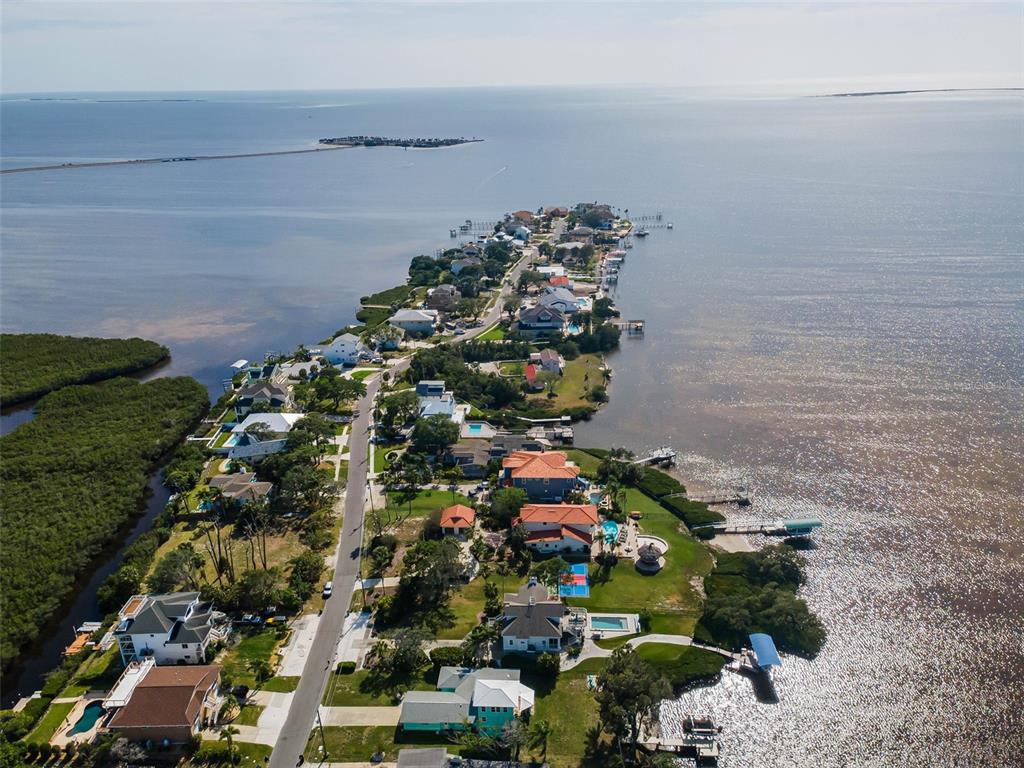 An aerial view shows a residential peninsula surrounded by water with docks and mangrove areas — 1626 SEA BREEZE DRIVE, TARPON SPRINGS, FL