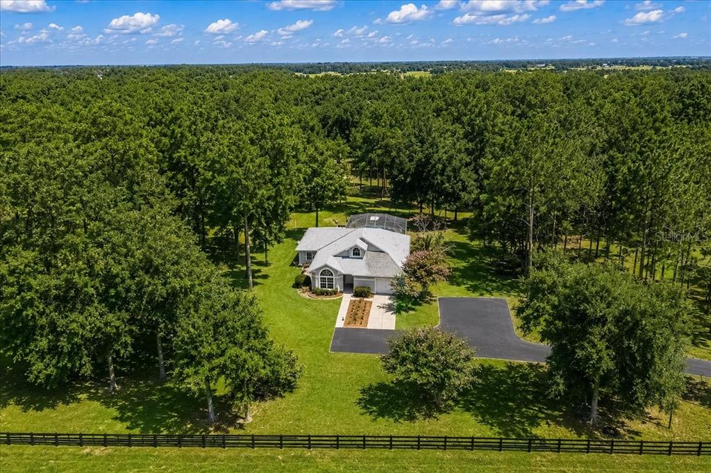 An aerial view shows a single-story house with a screened pool surrounded by dense woods — 855 NW 75TH TERRACE, OCALA, FL