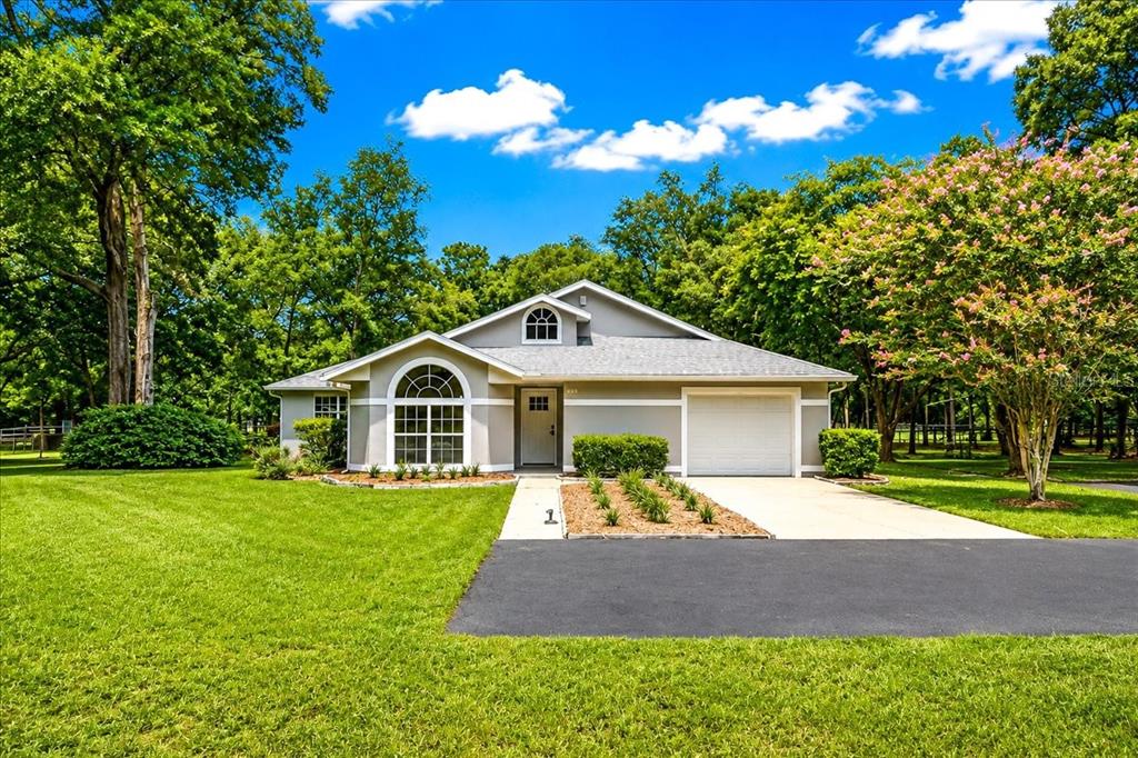 A single-story house with a gray exterior, arched window, and attached garage sits on a lawn — 855 NW 75TH TERRACE, OCALA, FL