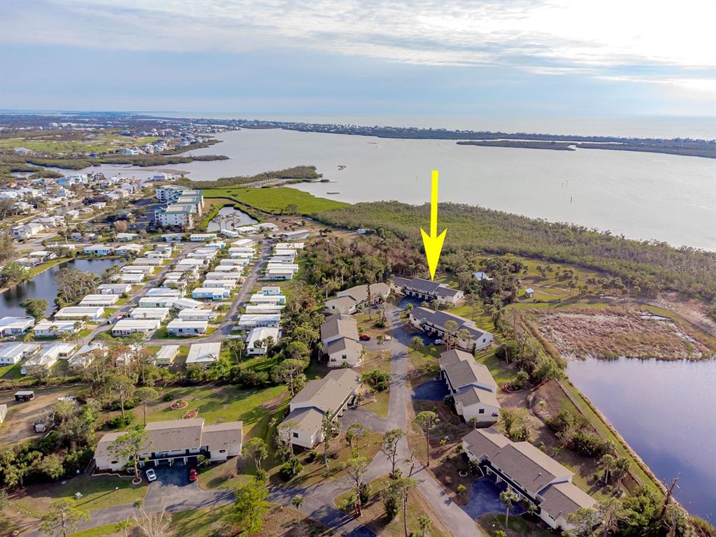 An aerial view shows a residential complex with multiple buildings near a body of water — 4260 PLACIDA ROAD UNIT 12C, ENGLEWOOD, FL