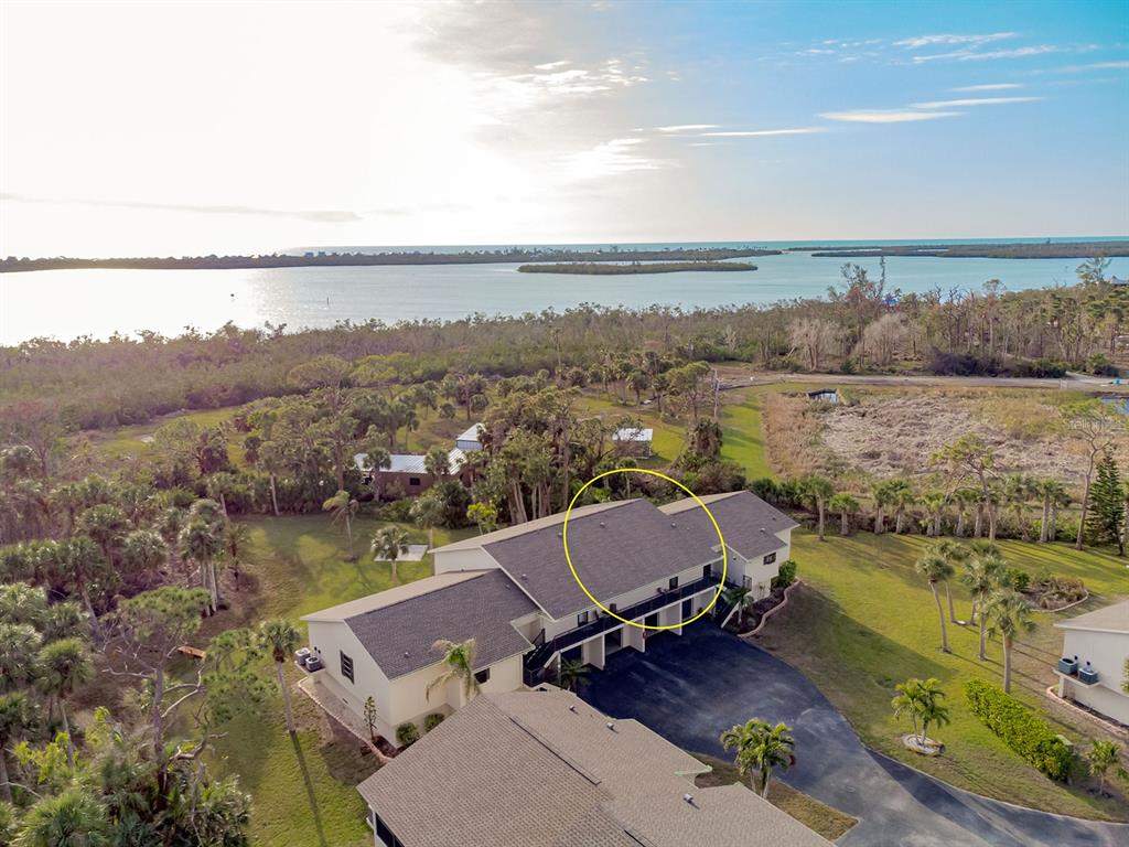 An aerial view shows a multi-unit residential building with a shingled roof near water — 4260 PLACIDA ROAD UNIT 12C, ENGLEWOOD, FL
