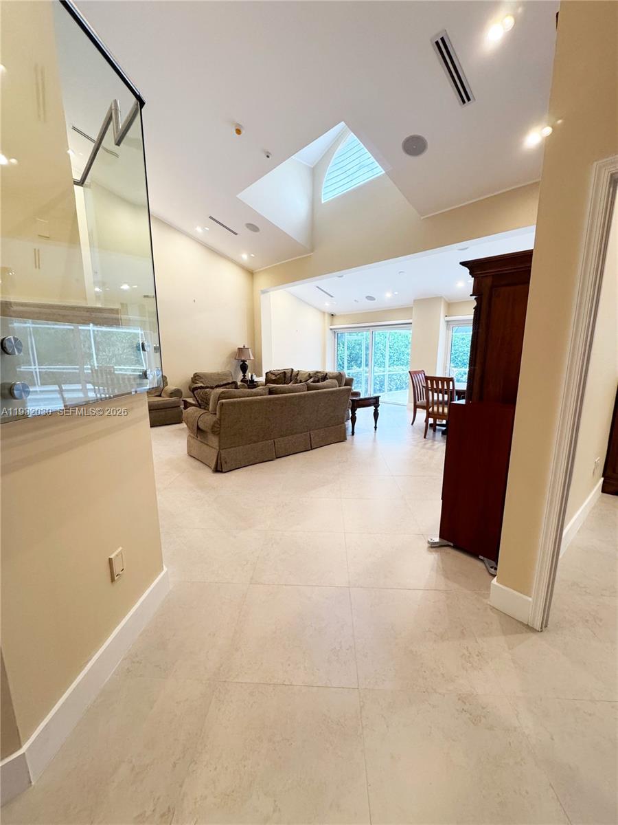A spacious living and dining area with high ceilings, a skylight, and light-colored tile flooring — 610 Misty Oaks Ln, Pompano Beach FL 33069, POMPANO BEACH, FL