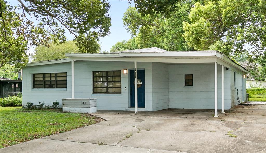 A light blue, single-story concrete block house features a front carport and a paved driveway — 141 COUNTRY CLUB DRIVE, SANFORD, FL