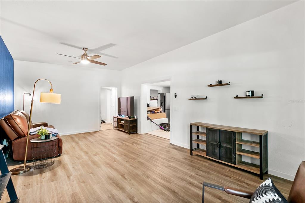 A living room features wood-look flooring, white walls, a ceiling fan, and a console table — 141 COUNTRY CLUB DRIVE, SANFORD, FL