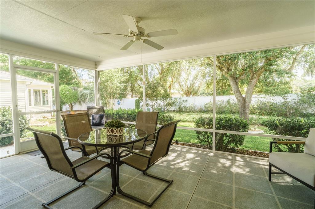 The exterior of a single-story house features a screened-in back porch and a grassy yard — 16980 SE 96TH CHAPELWOOD CIRCLE, THE VILLAGES, FL