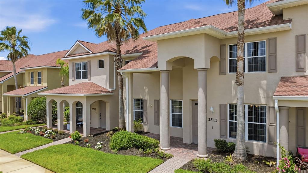 A two-story stucco townhouse with a covered entryway, columns, and a shingled roof — 3515 ROMEA CIRCLE, NEW SMYRNA BEACH, FL