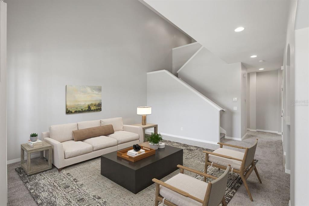 A living room features a beige sofa, two wooden chairs, a coffee table, and stairs — 3515 ROMEA CIRCLE, NEW SMYRNA BEACH, FL