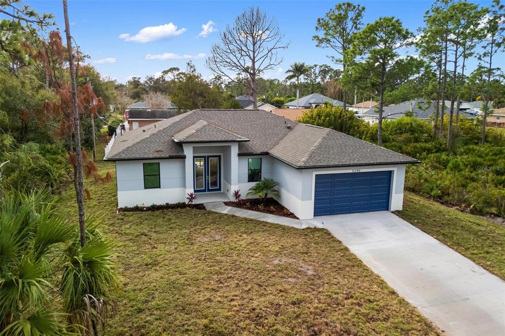 A single-story house with a blue garage door, light blue siding, and a concrete driveway — 5349 JESSAMINE AVENUE, NORTH PORT, FL