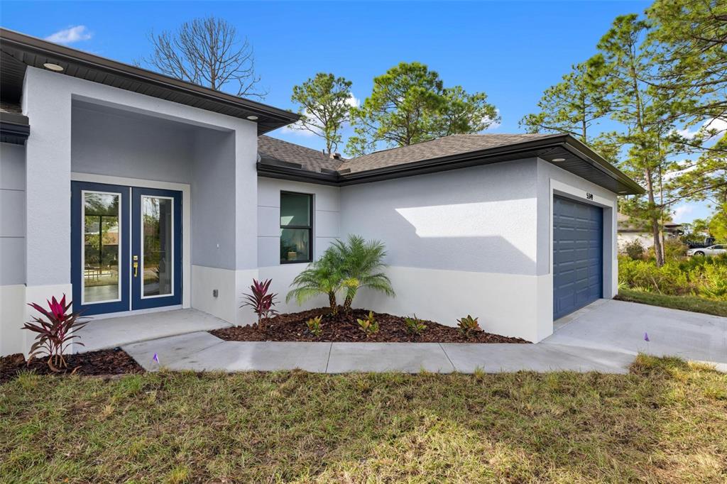 A light-colored house exterior features a blue double front door and a blue garage door — 5349 JESSAMINE AVENUE, NORTH PORT, FL