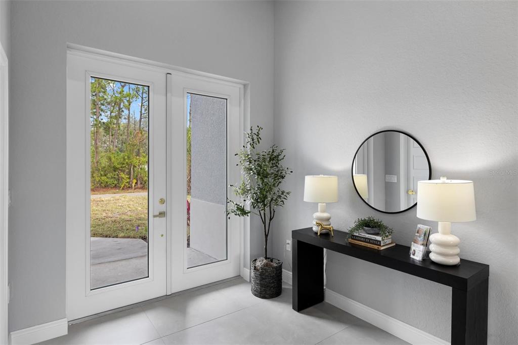 A bright entryway features white double doors, light tile flooring, and a black console table — 5349 JESSAMINE AVENUE, NORTH PORT, FL
