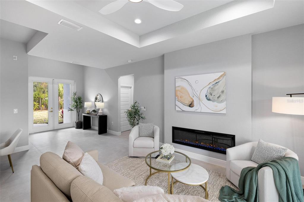 A living room features a linear fireplace, white armchairs, a beige sofa, and glass tables — 5349 JESSAMINE AVENUE, NORTH PORT, FL