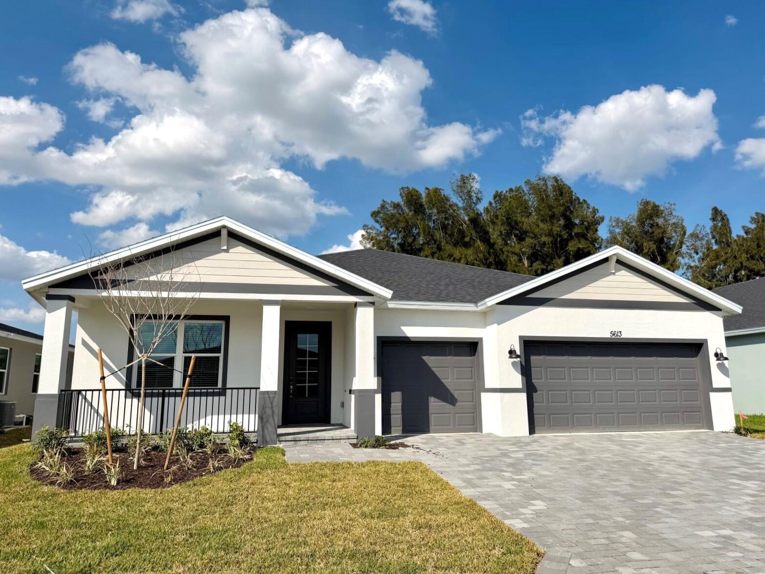 A single-story house with a white stucco exterior, dark gray trim, and a paved driveway — 5613 Hampton Park Circle, Vero Beach FL 32966, VERO BEACH, FL