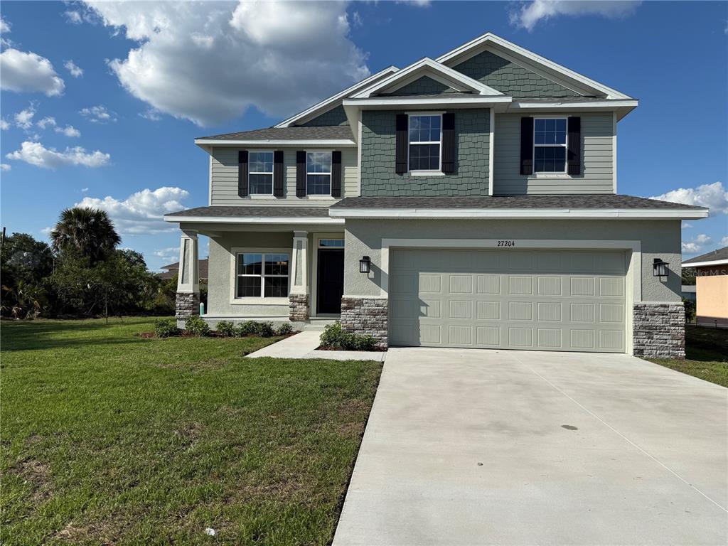 A two-story house features a light-colored facade, stone accents, and a two-car garage — 27204 DEEP CREEK BOULEVARD, PUNTA GORDA, FL