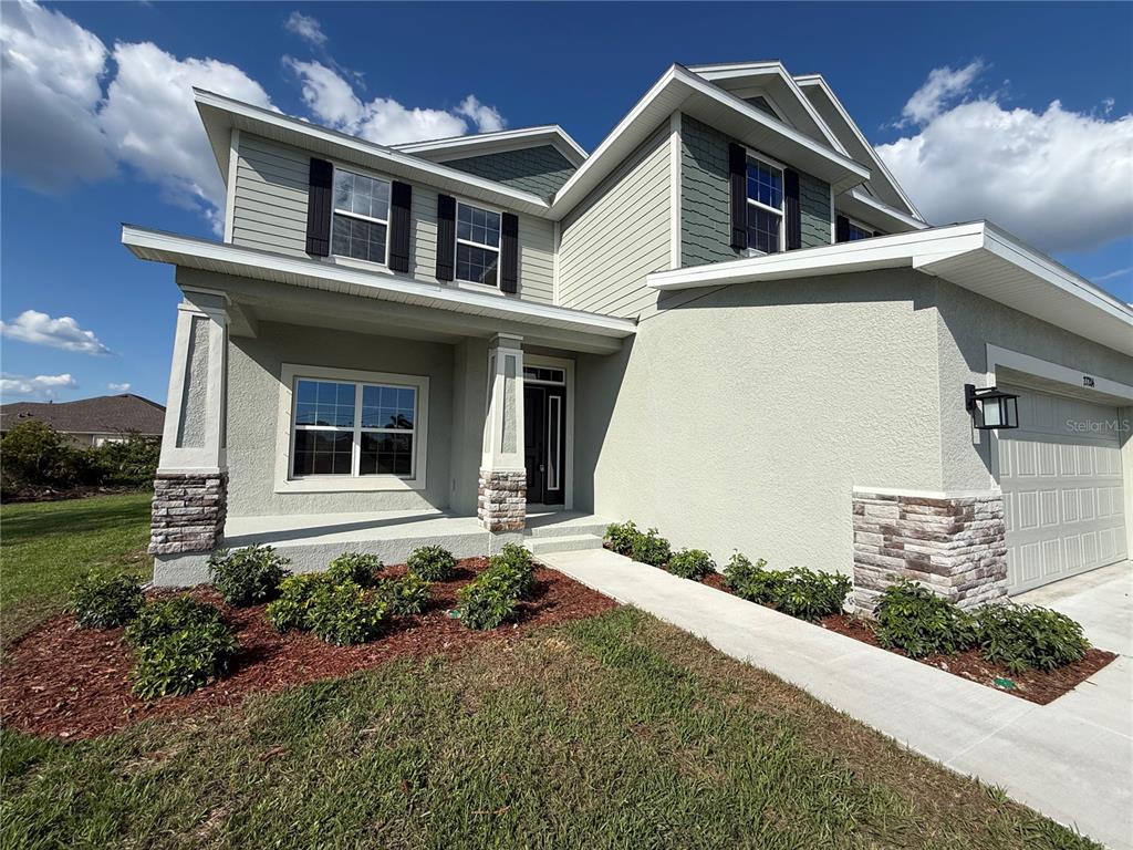 A two-story house with a light-colored stucco exterior, stone accents, and a front porch — 27204 DEEP CREEK BOULEVARD, PUNTA GORDA, FL