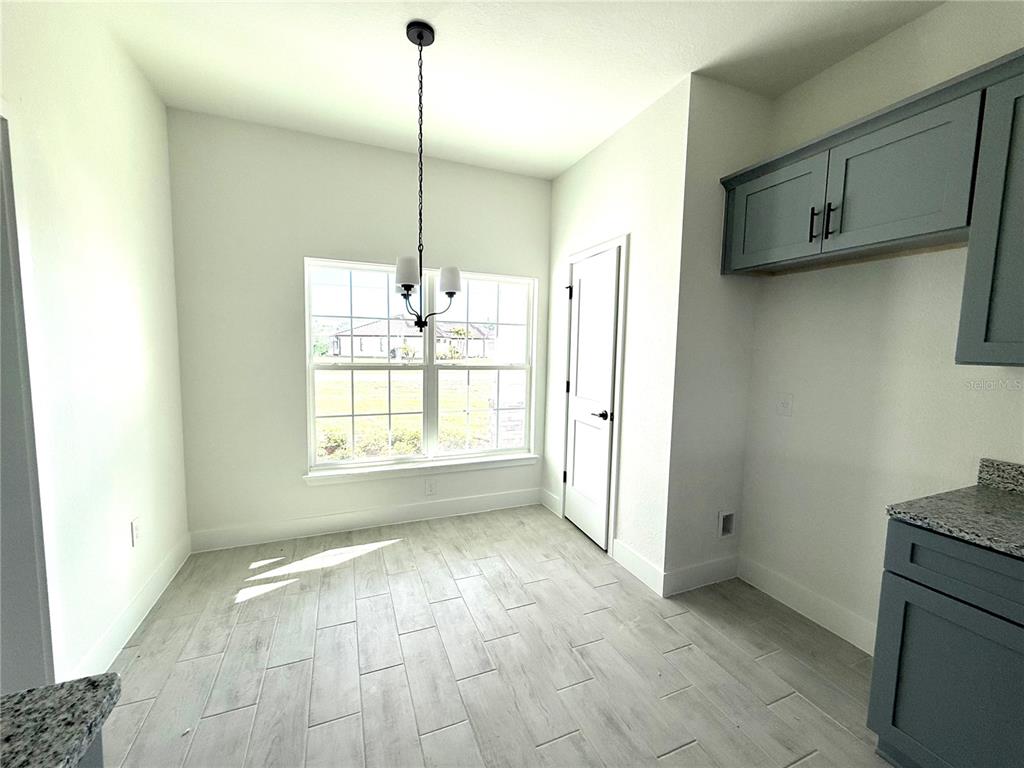 A dining area features light tile flooring, a window, a pendant light, and blue cabinetry — 27204 DEEP CREEK BOULEVARD, PUNTA GORDA, FL