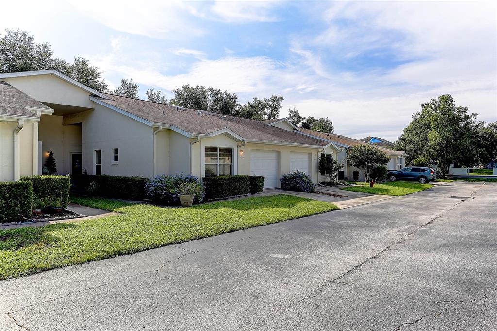 A row of single-story townhomes with attached garages and manicured lawns under a blue sky — 8405 TERRACE MEADOWS COURT UNIT 8405, TEMPLE TERRACE, FL