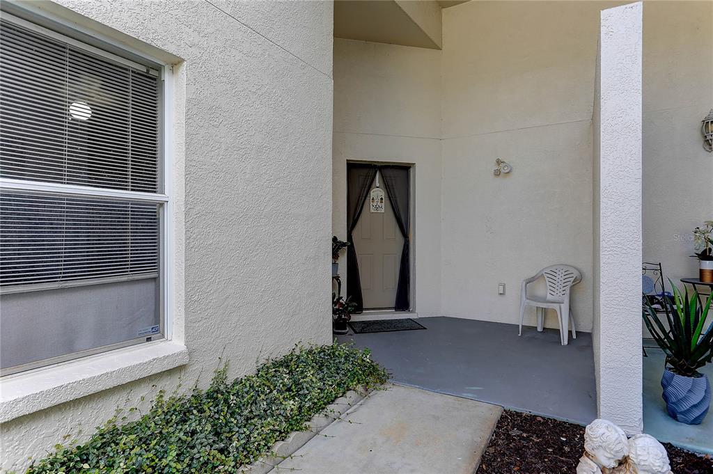 A concrete walkway leads to the front entrance of a stucco home with a patio — 8405 TERRACE MEADOWS COURT UNIT 8405, TEMPLE TERRACE, FL