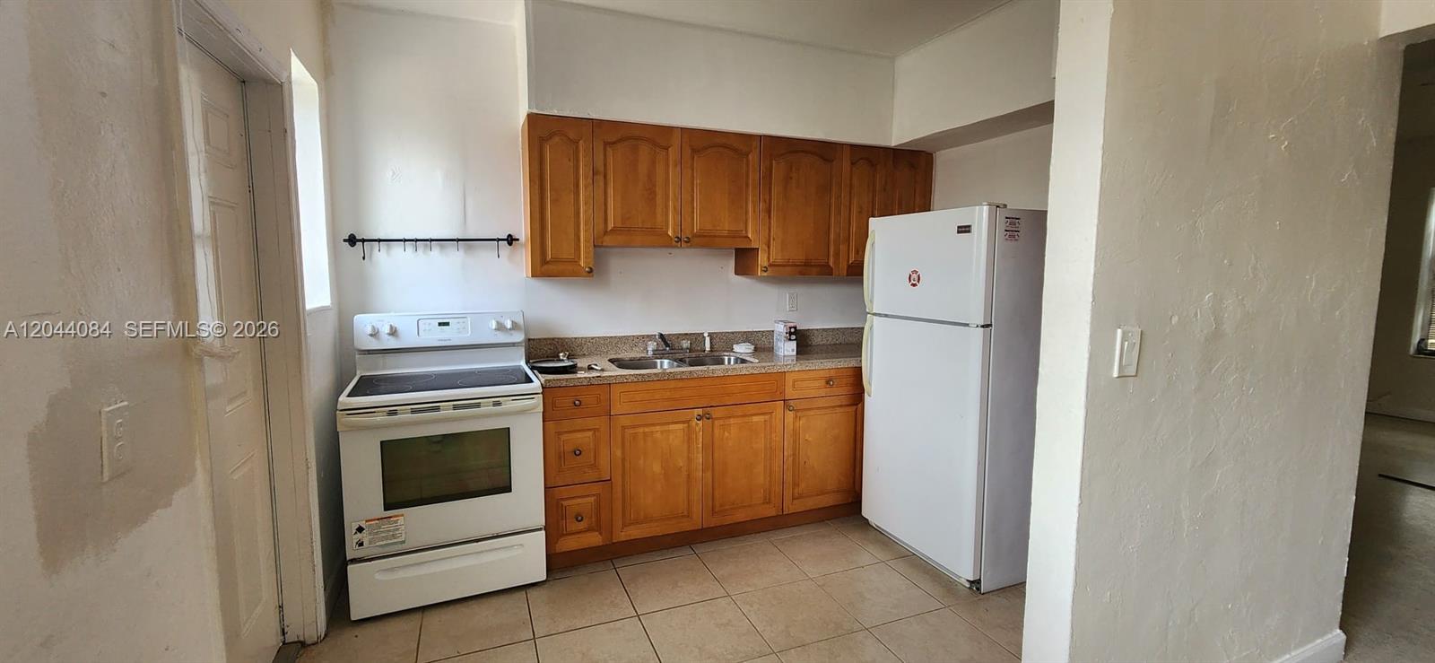 A kitchen features wood cabinets, a white stove, a white refrigerator, and tile flooring — 730 83rd St # 2, Miami Beach FL 33141, MIAMI BEACH, FL