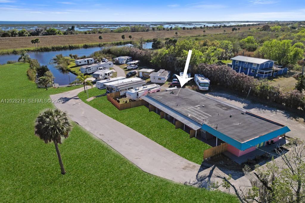 An aerial view shows a flat-roofed building with a pink facade near several parked RVs — 1422 US Highway 441, Okeechobee FL 34974, OKEECHOBEE, FL